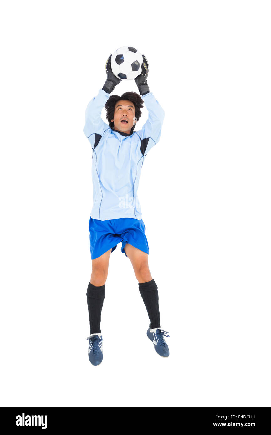 Goalkeeper in blue saving ball Stock Photo