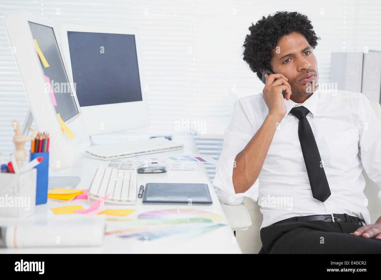 Serious businessman working at his desk on the phone Stock Photo
