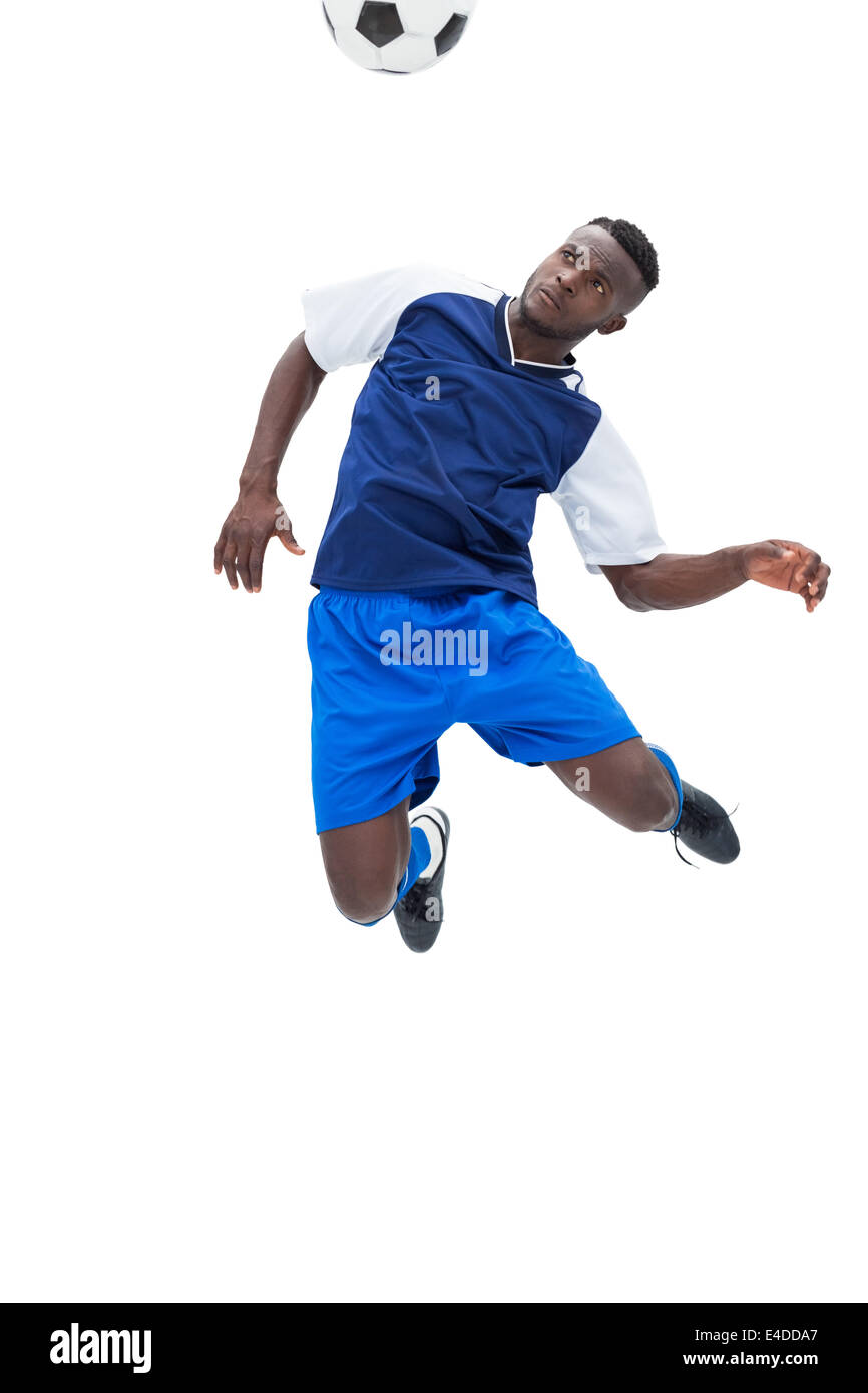 Football player in blue heading ball Stock Photo