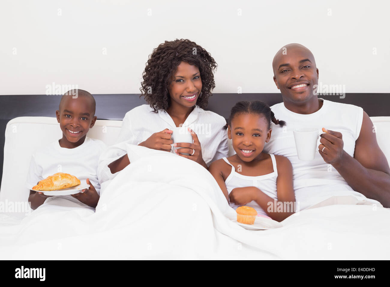Happy family having breakfast in bed Stock Photo - Alamy
