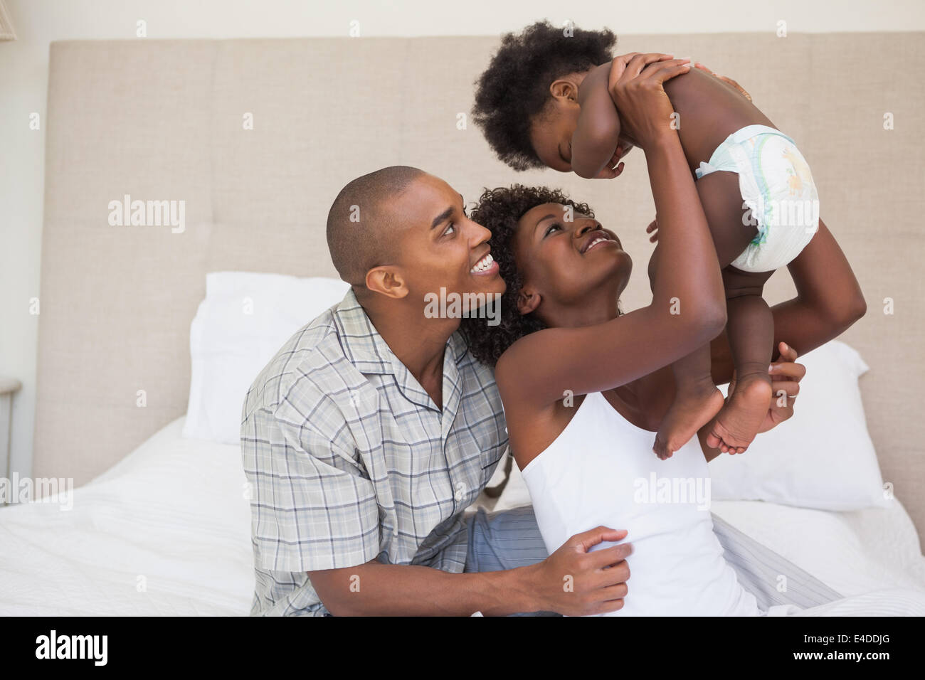 Happy parents with baby girl on the bed Stock Photo