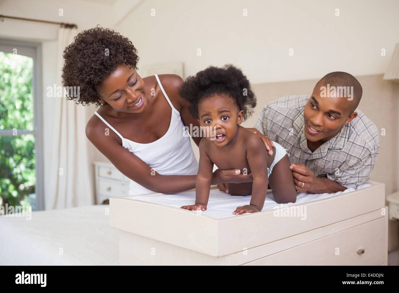 Happy parents with their baby girl on changing table Stock Photo