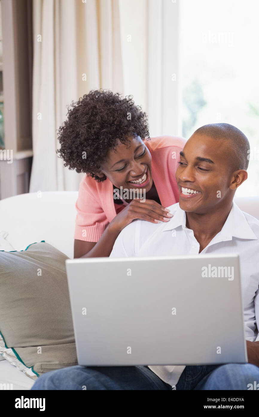 Happy couple relaxing on the couch with laptop Stock Photo - Alamy