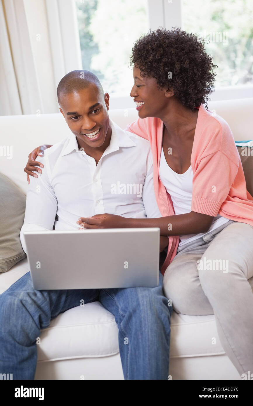 Happy couple relaxing on the couch with laptop Stock Photo - Alamy