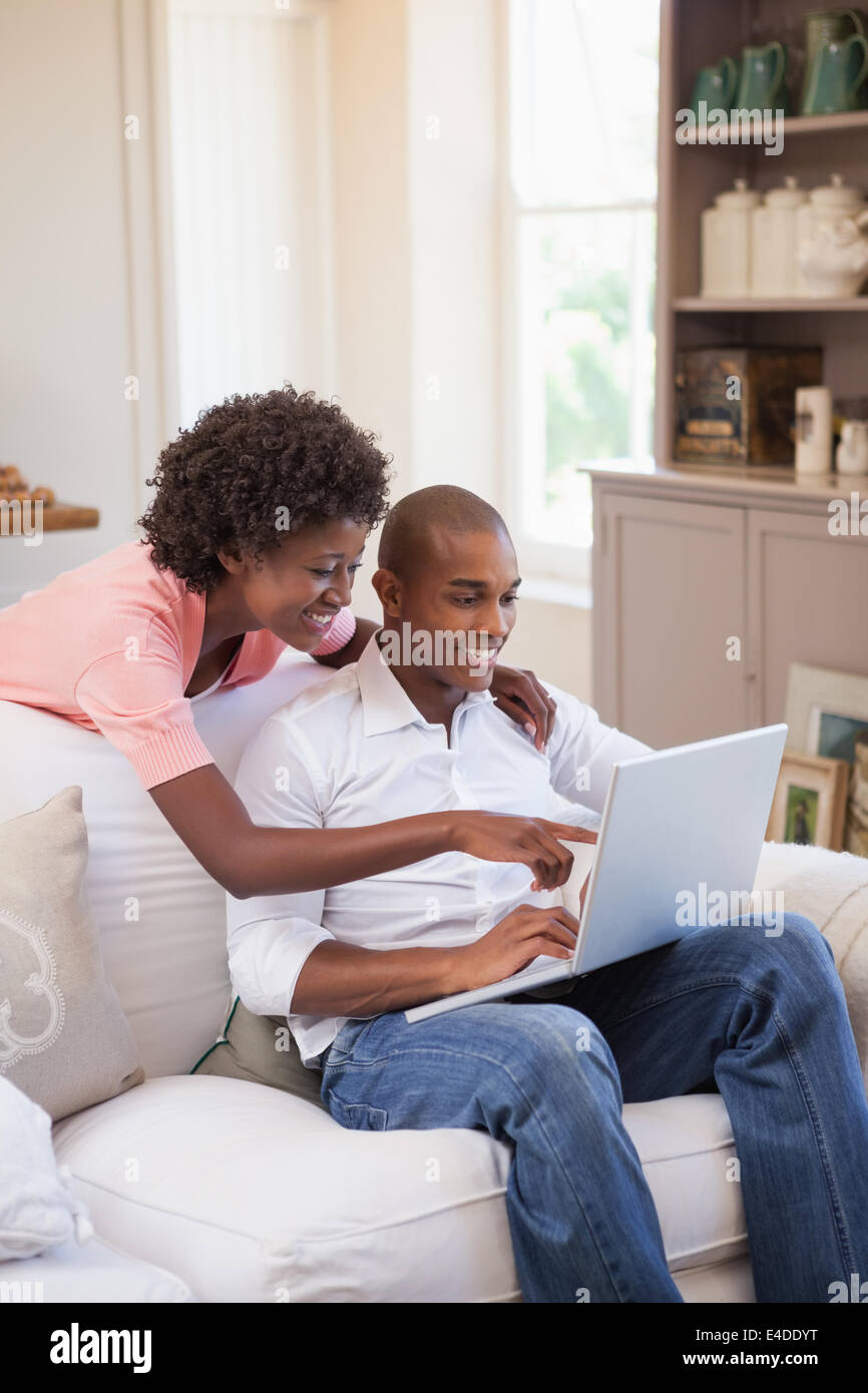 Happy couple relaxing together on the couch using laptop Stock Photo ...
