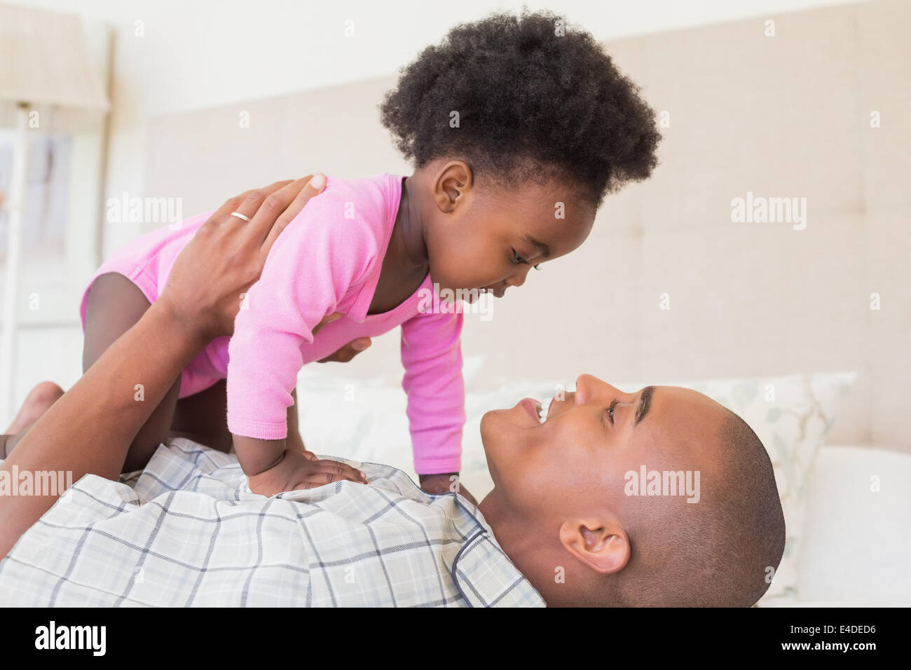 Father and baby girl lying on bed together Stock Photo