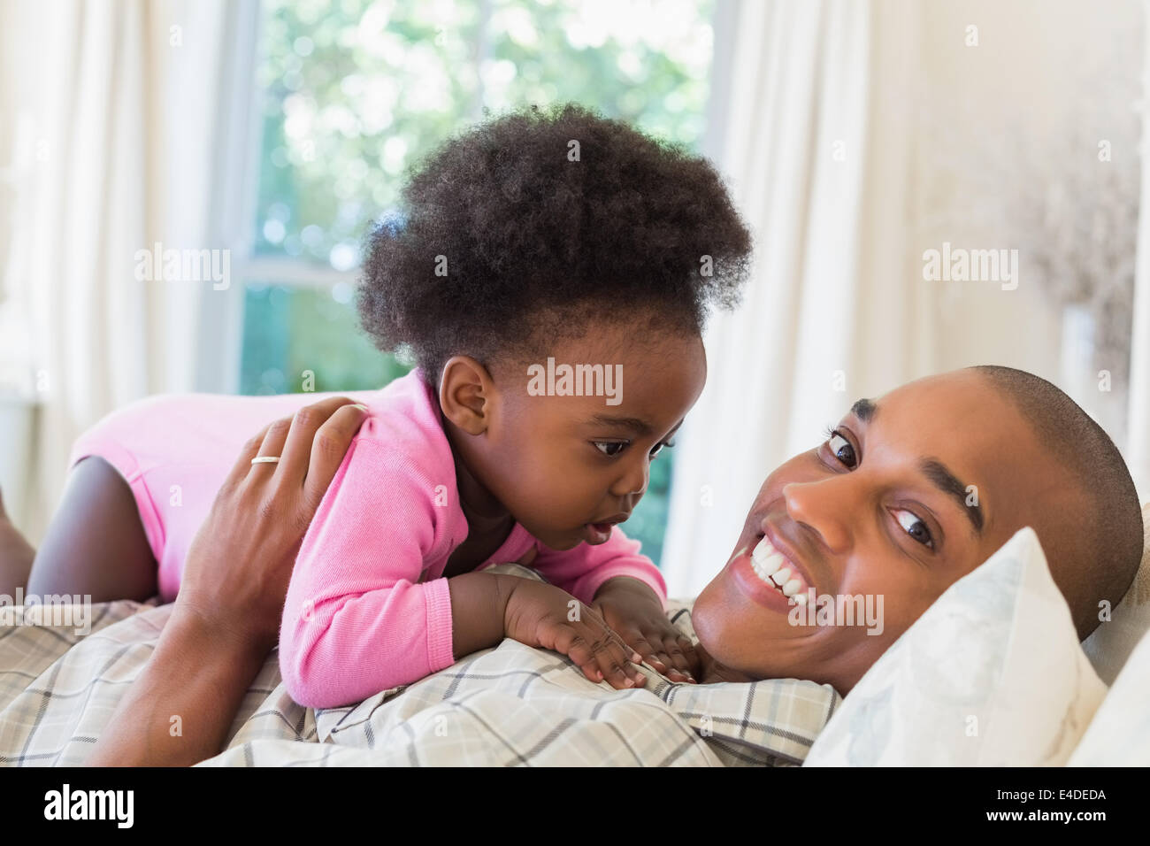 Happy father and baby girl lying on bed together Stock Photo