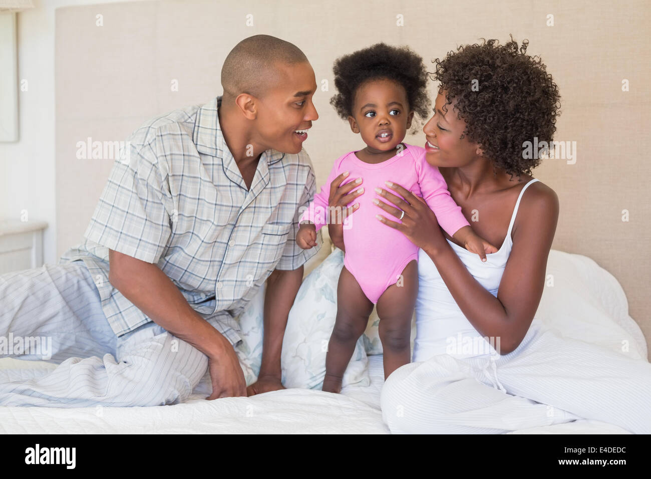 Happy parents and baby girl on bed together Stock Photo