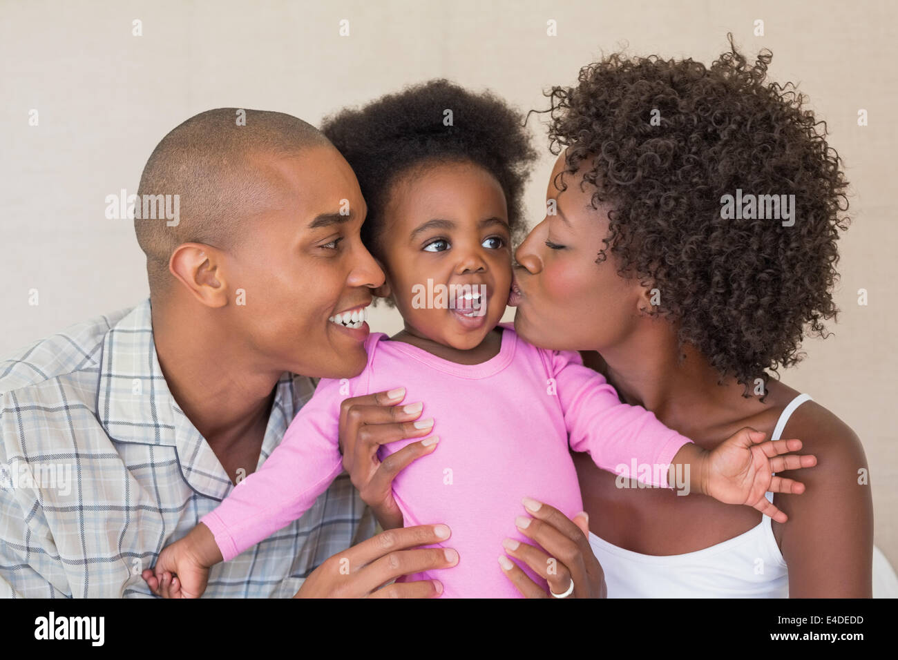 Happy parents and baby girl on bed together Stock Photo