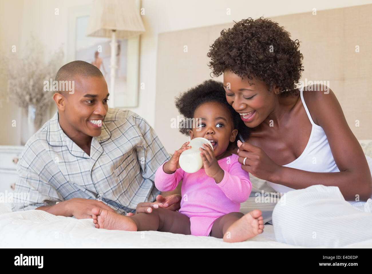 Happy parents with baby girl on their bed Stock Photo