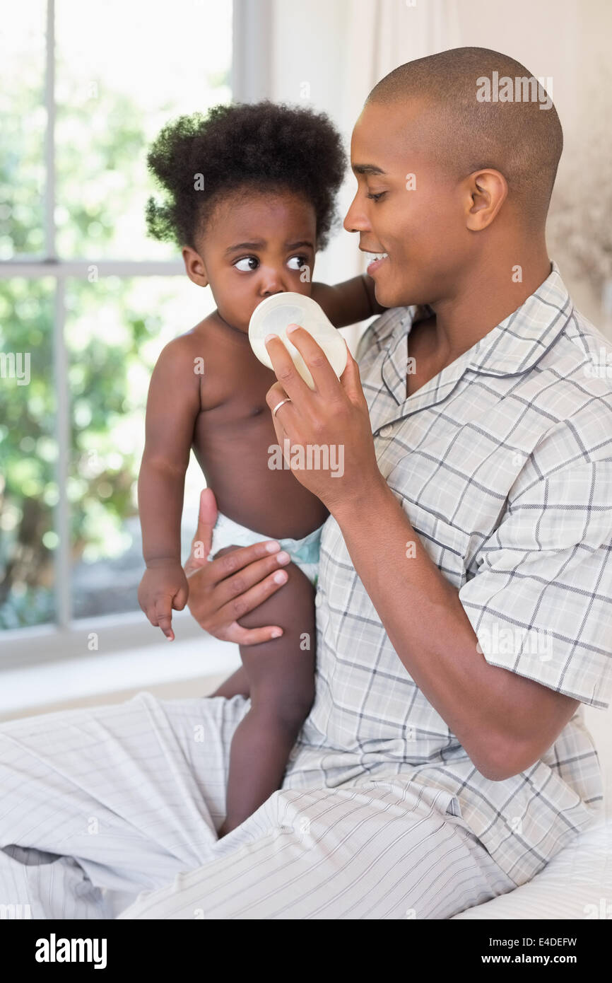 Happy father trying to feeding his baby girl Stock Photo