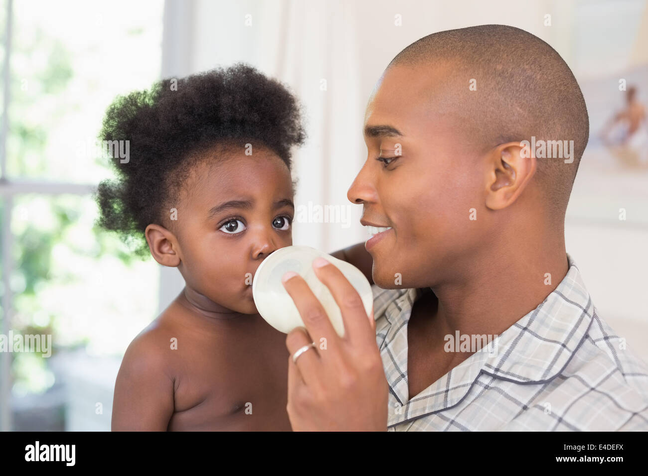 Happy father trying to feeding his baby girl Stock Photo
