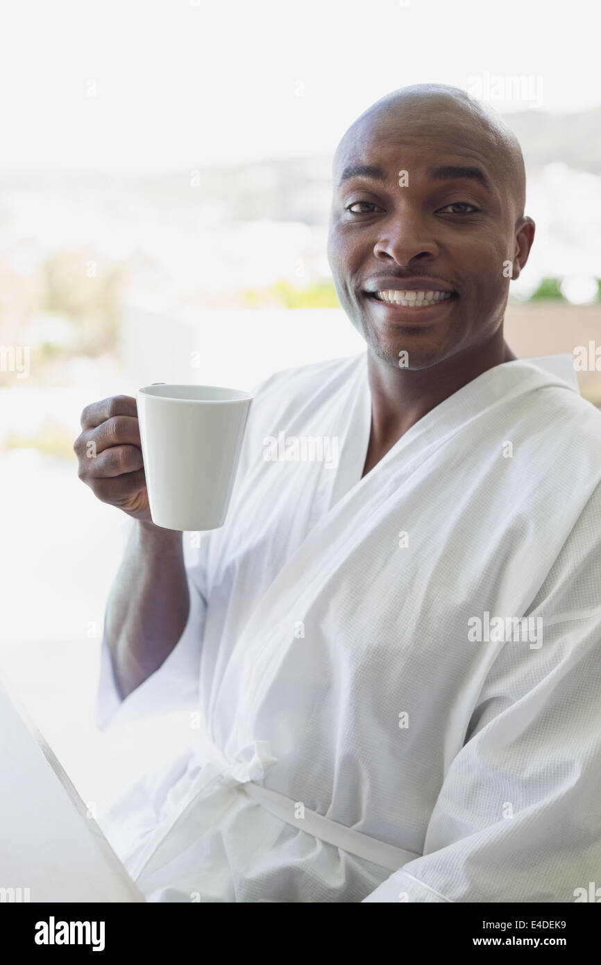 Handsome man in bathrobe drinking coffee outside Stock Photo