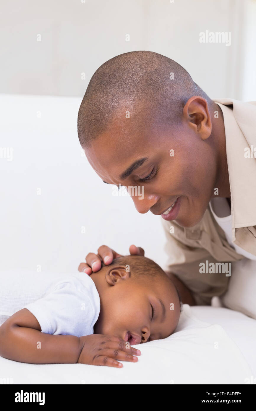Adorable baby boy sleeping while being watched by father Stock Photo