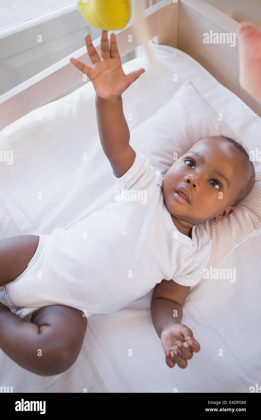 Adorable baby boy lying in his crib playing with mobile Stock Photo