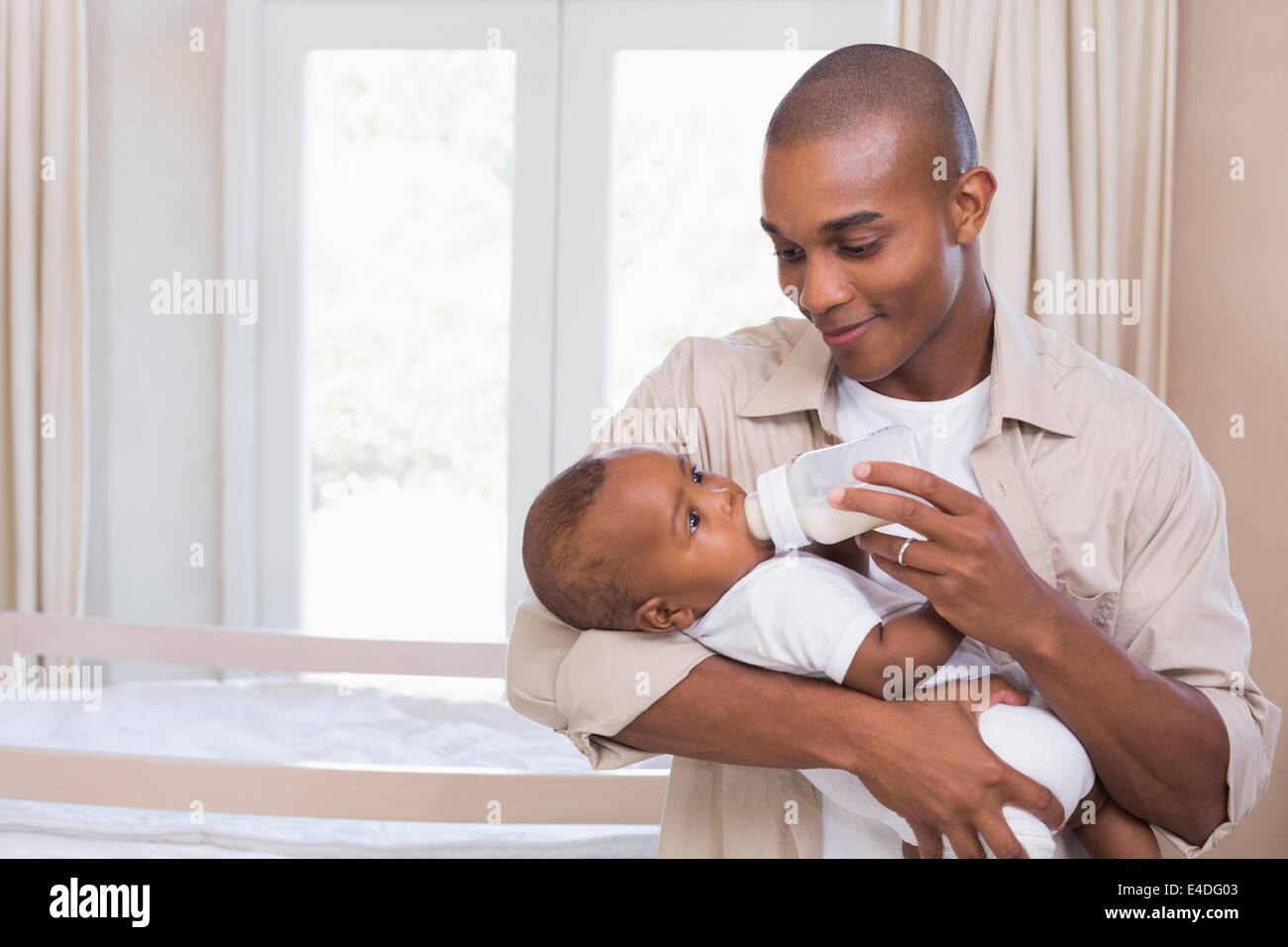 Happy father feeding his baby boy a bottle Stock Photo