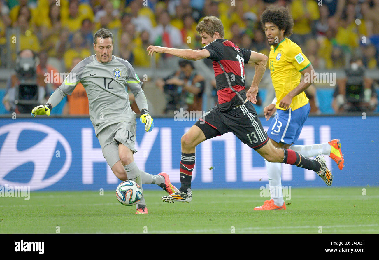 Belo Horizonte, Brazil. 8th July, 2014. Germany's Thomas Mueller (C) and Brazil's goal keeper Julio Cesar and Dante vie for the ball during the FIFA World Cup 2014 semi-final soccer match between Brazil and Germany at Estadio Mineirao in Belo Horizonte, Brazil, 08 July 2014. Photo: Thomas Eisenhuth/dpa/Alamy Live News Stock Photo