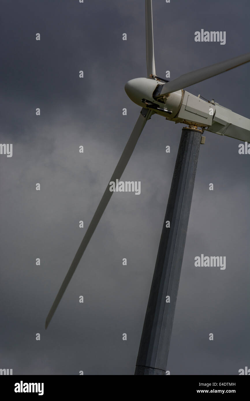 Wind turbine / wind generator set against brooding / foreboding dark clouds. A 'renewable' form of power useful in the climate change energy mix. Stock Photo