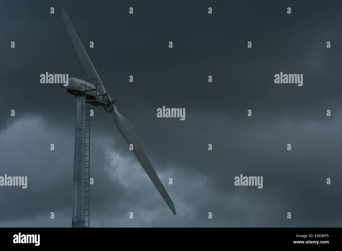 Wind turbine / wind generator set against brooding / foreboding dark clouds. Stock Photo