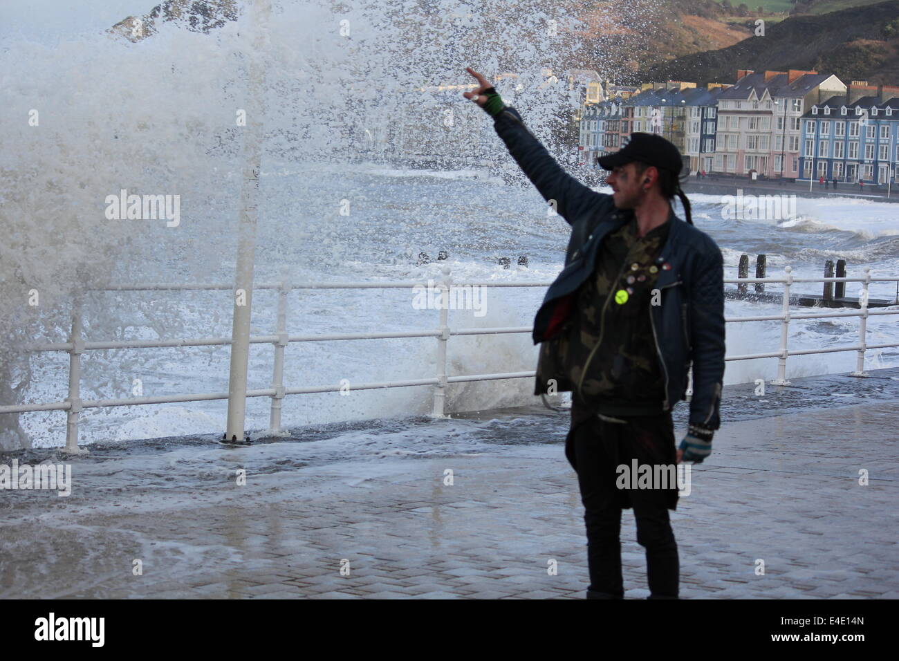 A punk style man posing in front of stormy seas on aberystwyth promenade Stock Photo
