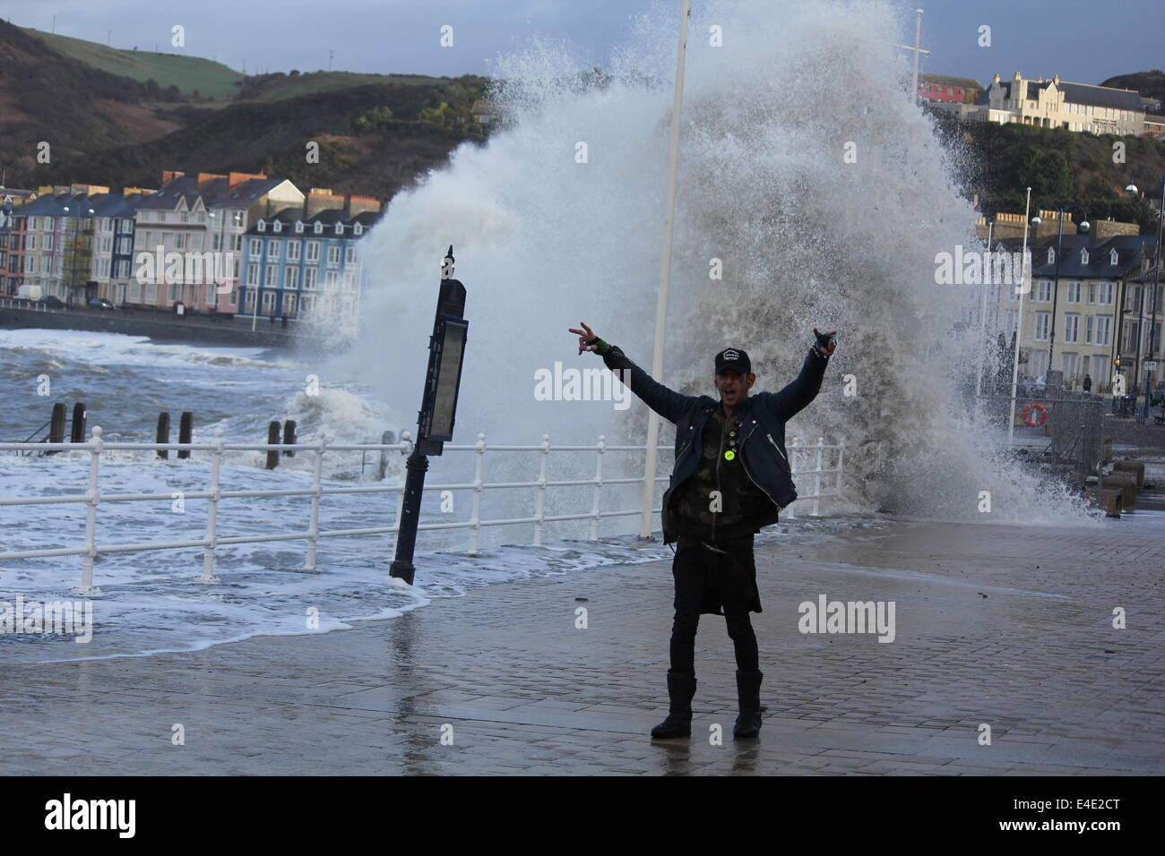 A punk style man posing in front of stormy seas on Aberystwyth promenade Stock Photo