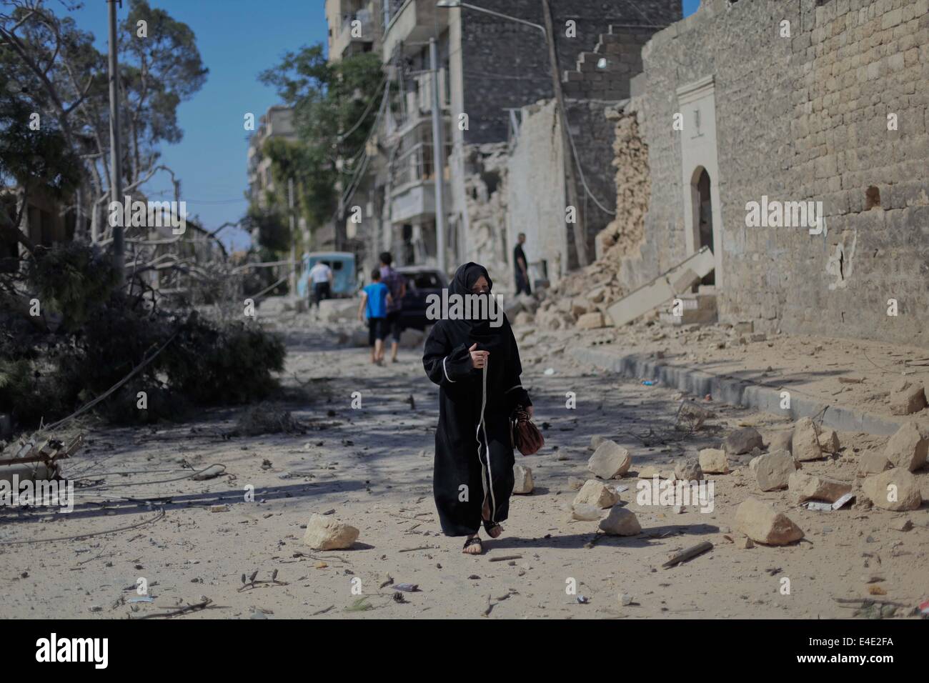 Aleppo, Syria. 8th July, 2014. A Syrian woman walks amid rubble of what activists said it was a barrel-bomb by aircraft loyal to Syria's president Bashar al-Assad on Qadi Askar neighbourhood in Aleppo on July 8, 2014. The Civil Defence loyal to the Free Syrian Army reported that the attack killed two women and injured others. Credit:  Ahmed Deeb/NurPhoto/ZUMA Wire/Alamy Live News Stock Photo