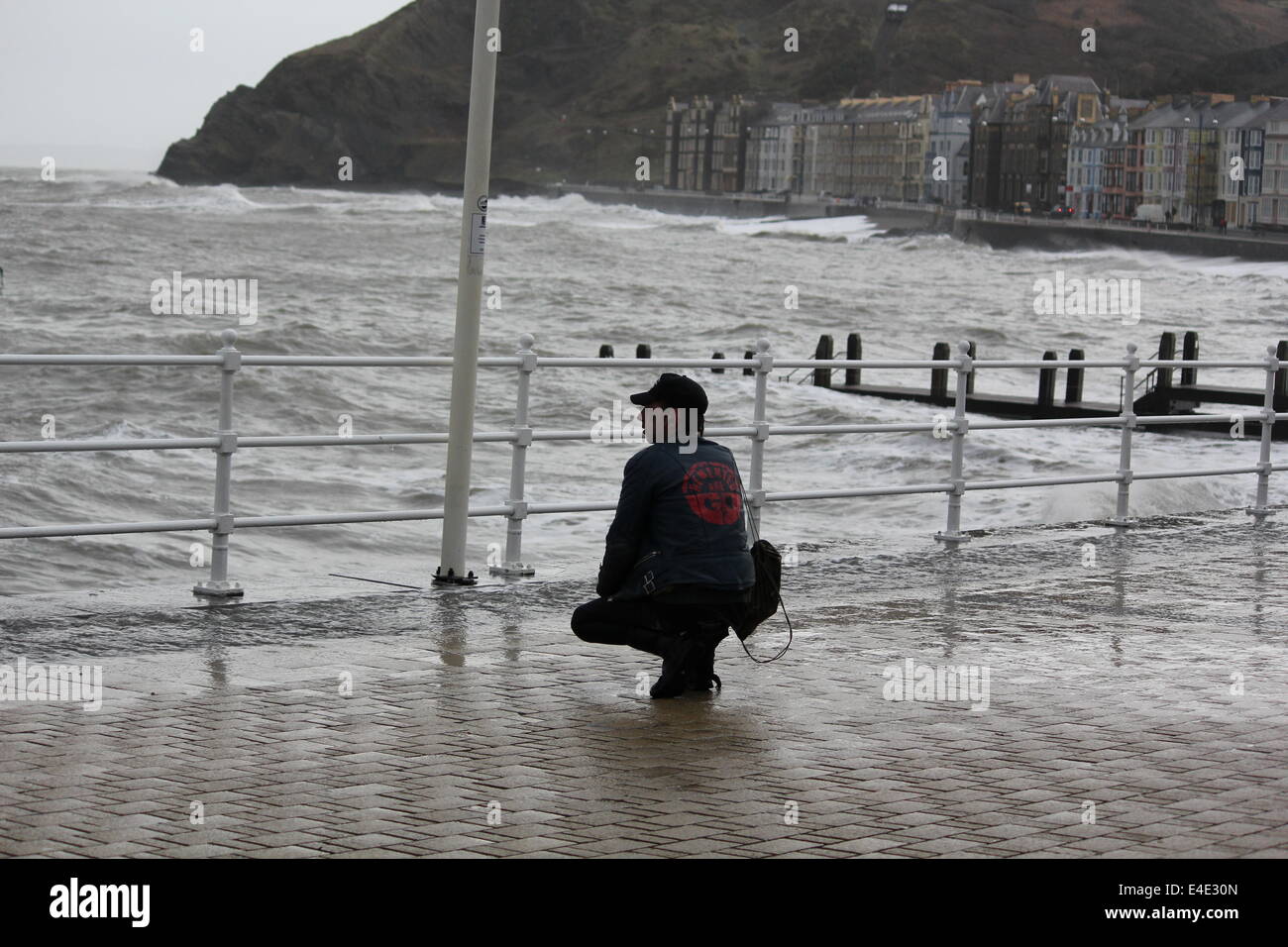 A punk style man posing on Aberystwyth promenade in front of stormy seas Stock Photo