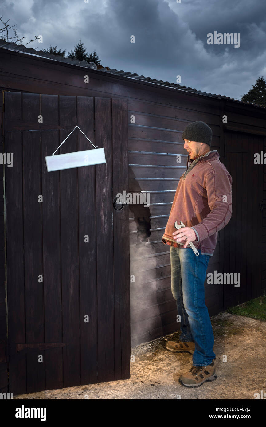 Man looking with horror at a fire in his workshop. Stock Photo