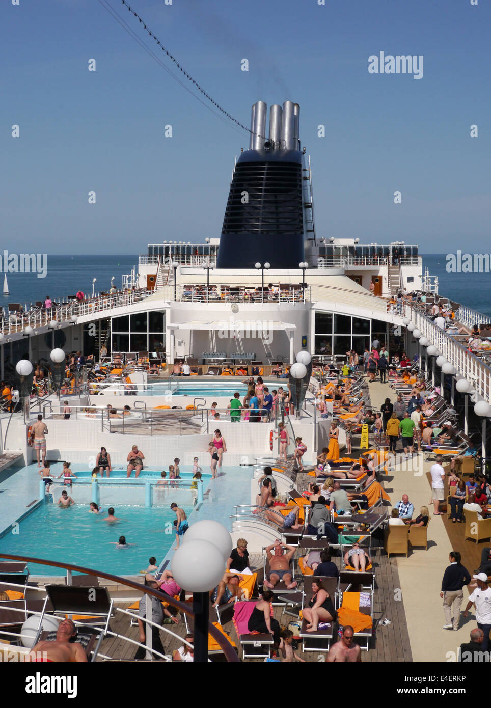 The Top Deck Of A Busy Cruise Ship With People Sitting Around The Pool On A Sunny Day Stock Photo Alamy