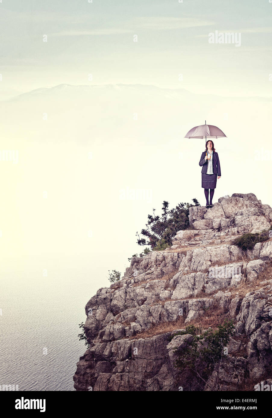 woman with umbrella on rock cliff Stock Photo