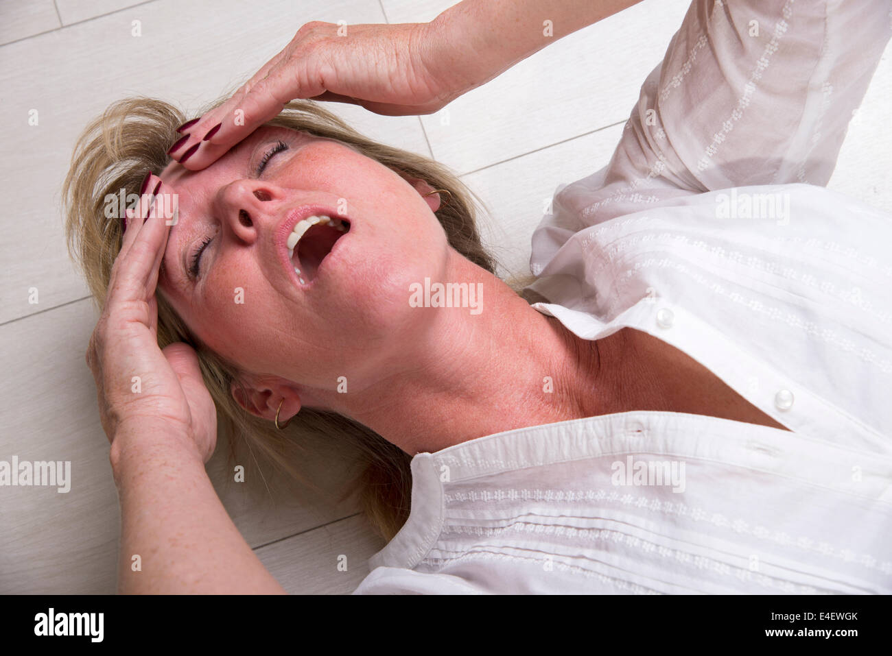 Woman laying on the floor with mouth open Stock Photo