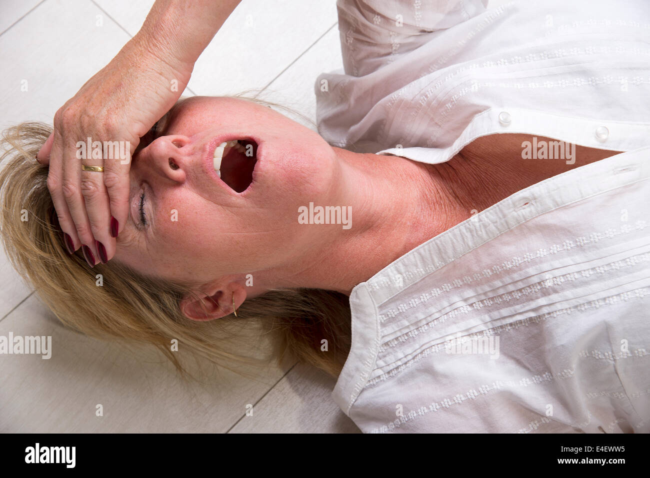 Woman laying on the floor with mouth open Stock Photo