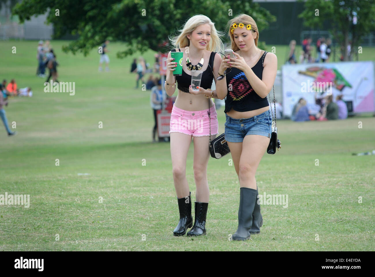 YOUNG GIRLS ENJOYING SOCIAL MEDIA  AT  A OUTDOOR MUSIC FESTIVAL RE SUMMER FESTIVALS MOBILE PHONES TEENAGERS SOCIAL EVENTS UK Stock Photo