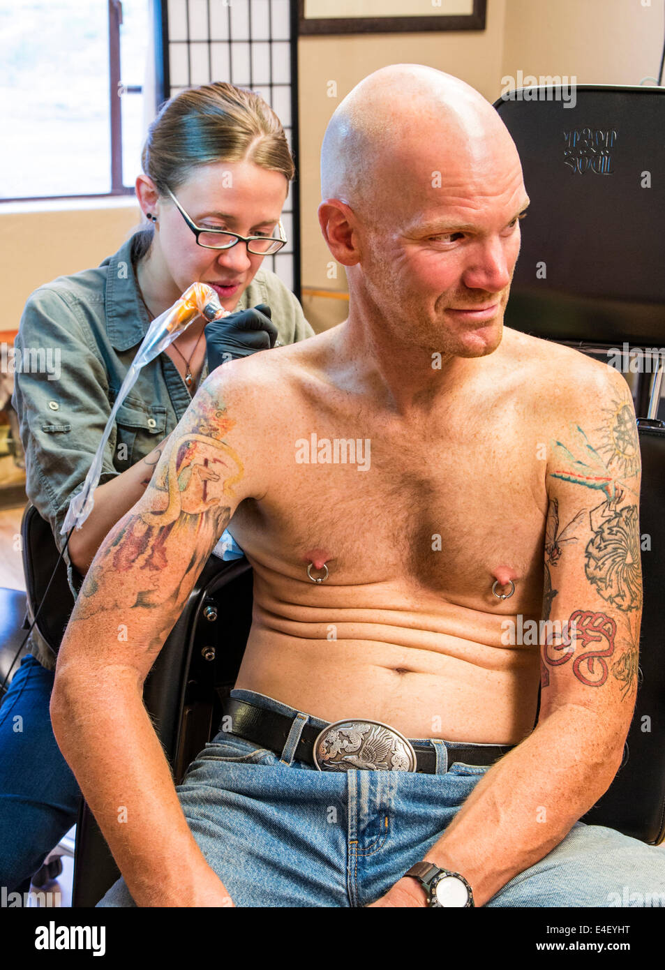 Woman tattooing an eagle on the back of a man Stock Photo