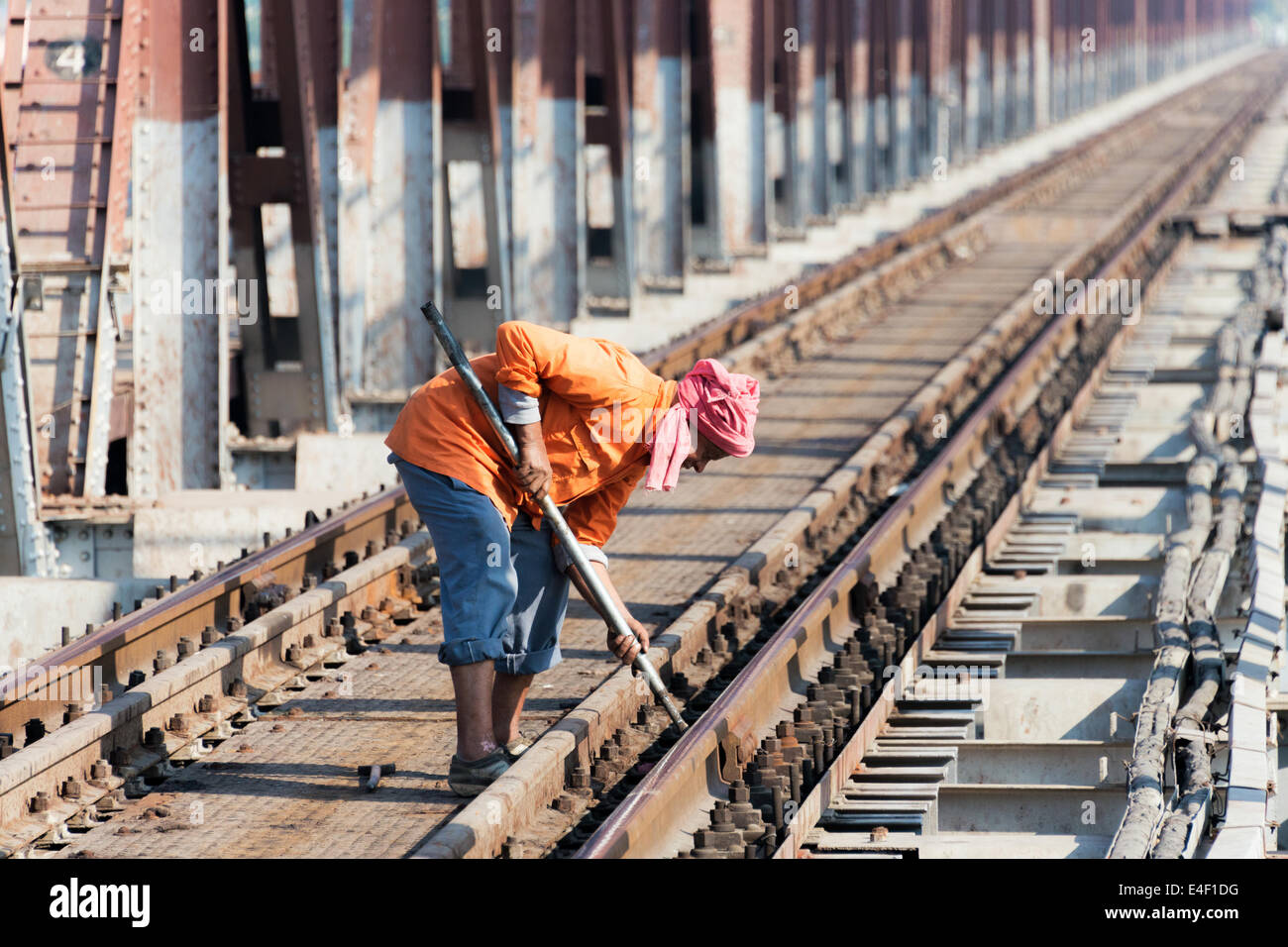 AGRA, INDIA - DECEMBER 2013: An Indian railway worker tightens a bolt on a railway track in Agra, India in December 2013. Stock Photo