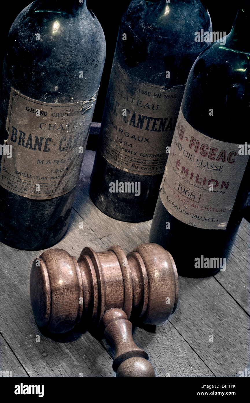 WINE AUCTION Bordeaux wine bottles vintage old dusty, Margaux and St. Emilion on wine barrel with auctioneers gavel in foreground Stock Photo