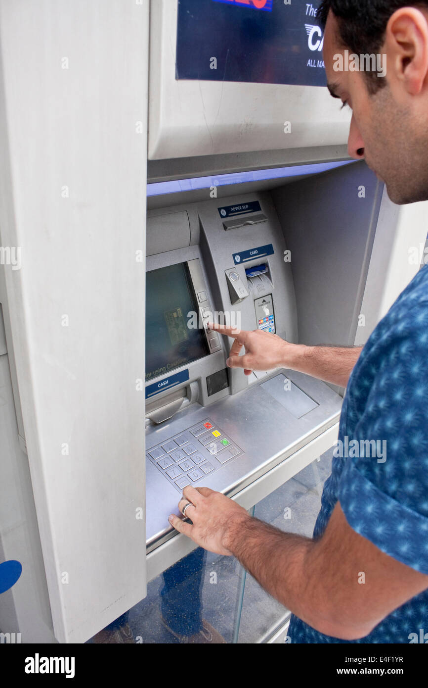 A male using an ATM machine Stock Photo