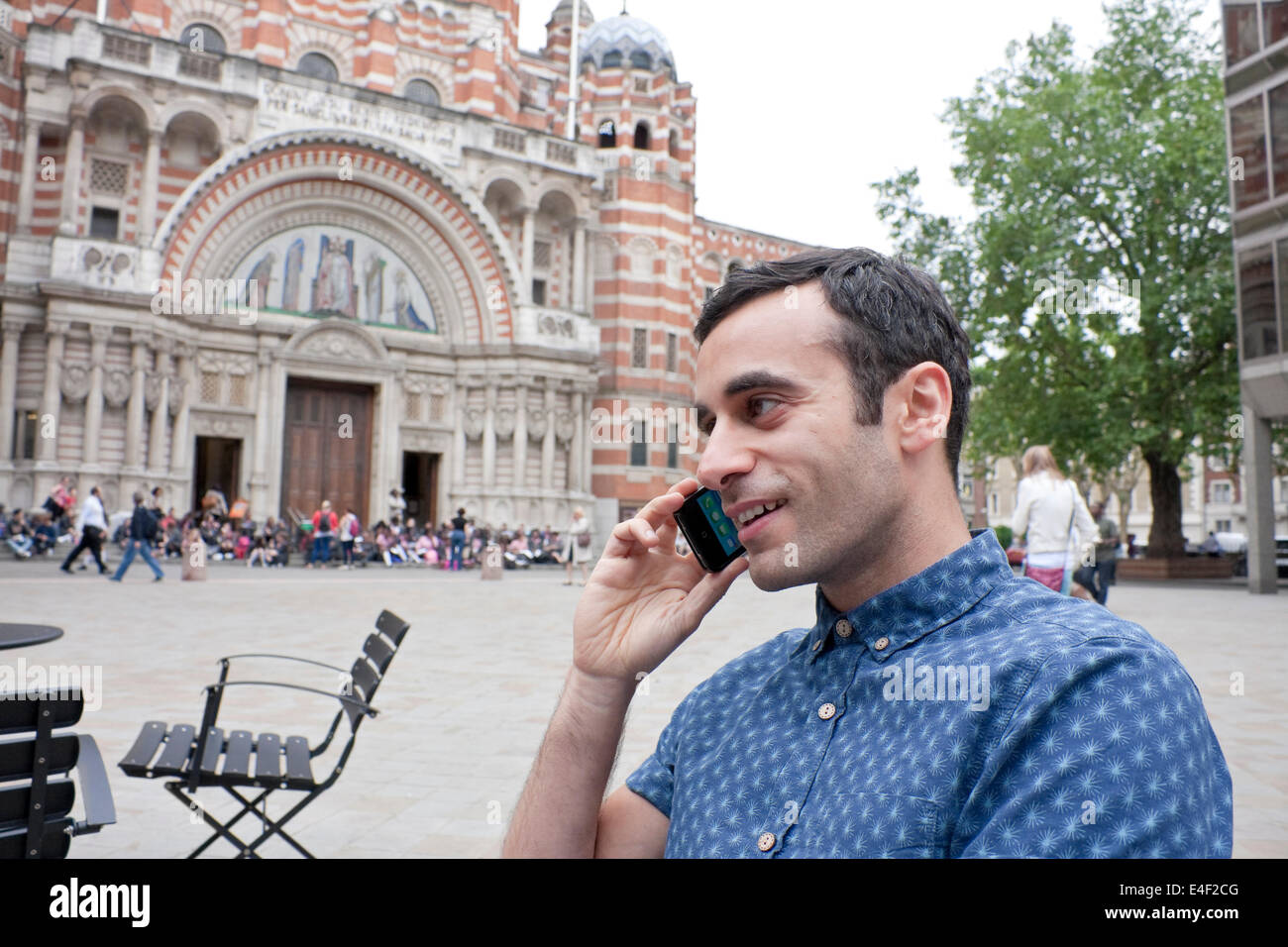 A mediterranean male talking on his smart phone sat outside in a plaza Stock Photo