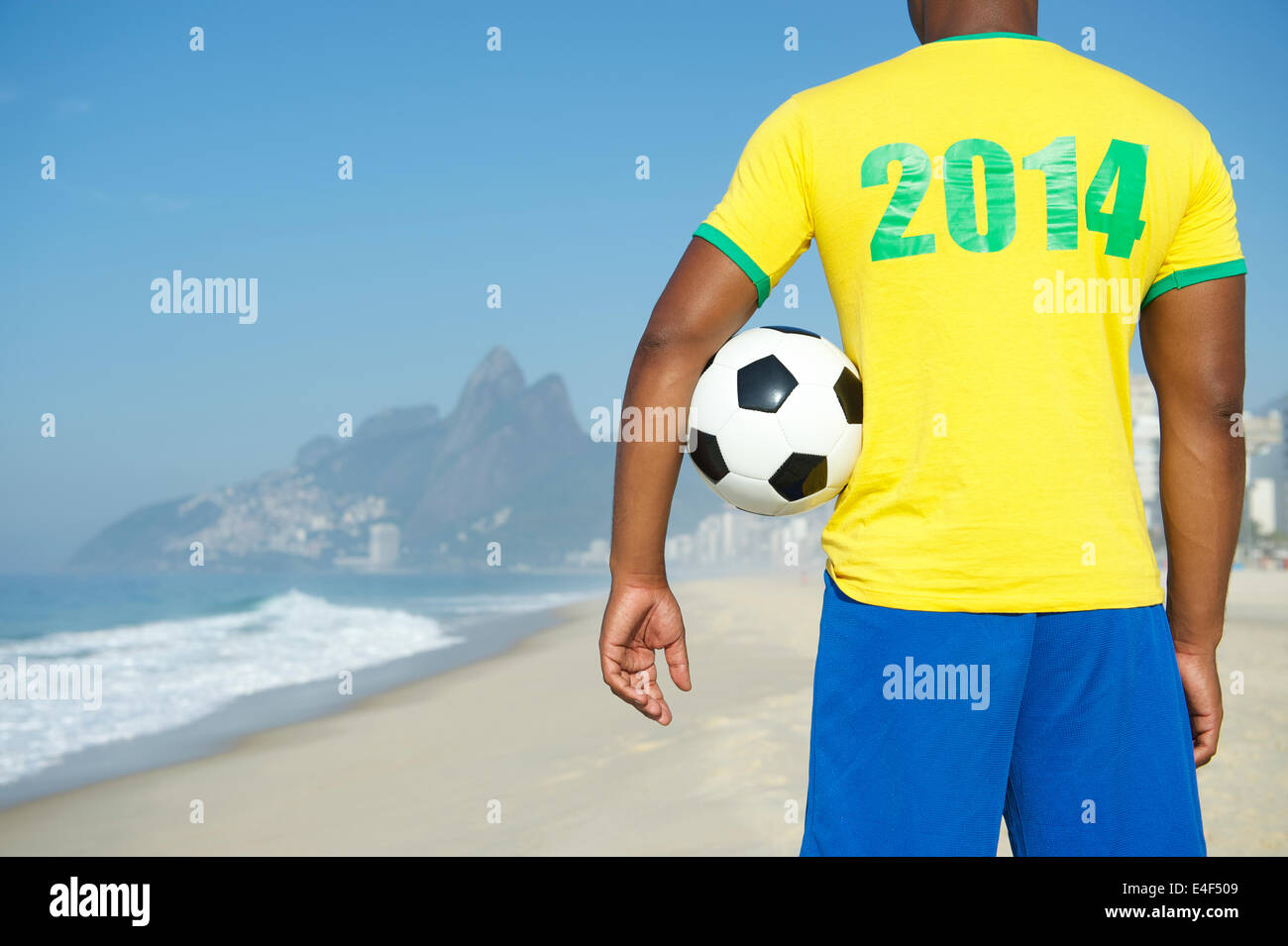 Brazil 2014 footballer in team Brazil kit holding classic soccer ball Ipanema Beach Rio de Janeiro Stock Photo
