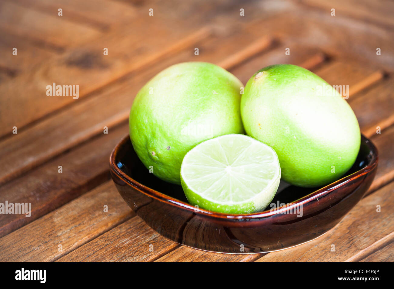 Fresh lime wholes and slice on wood background Stock Photo