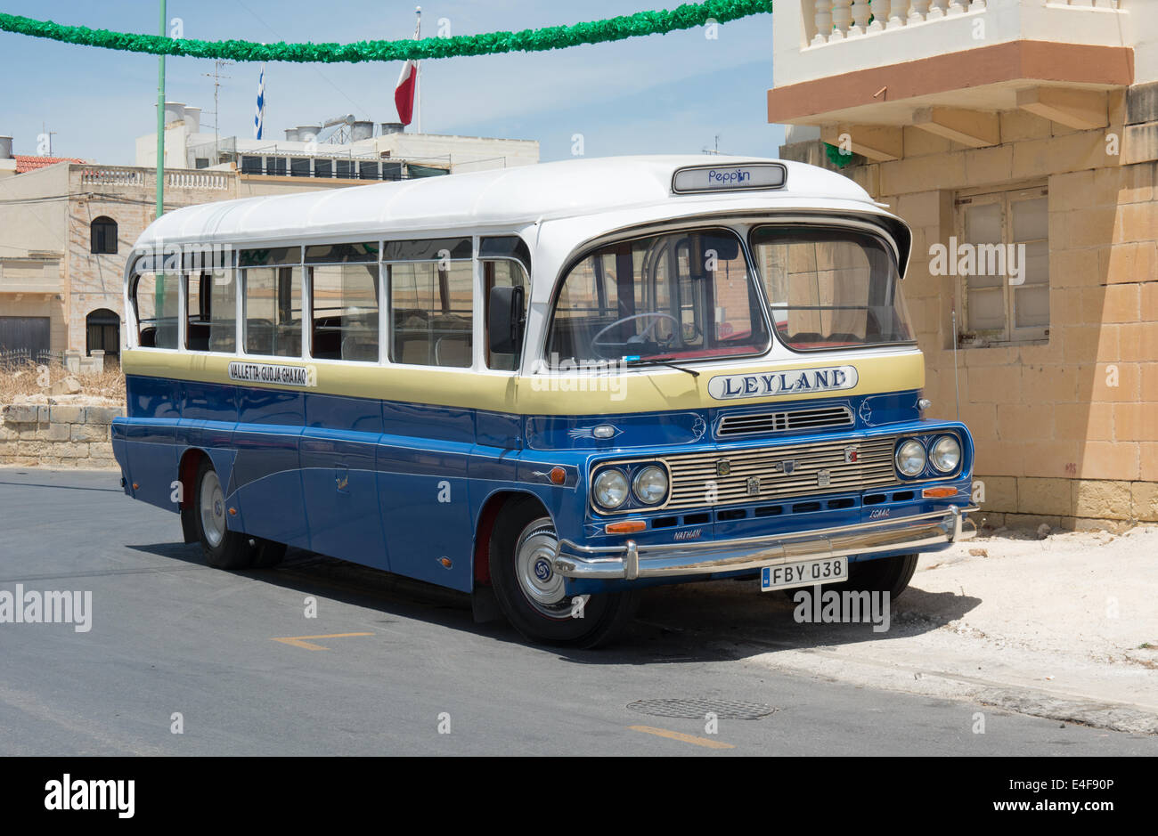 A restored Maltese bus stands in the sunshine. It has been painted into traditional village bus colours. Stock Photo