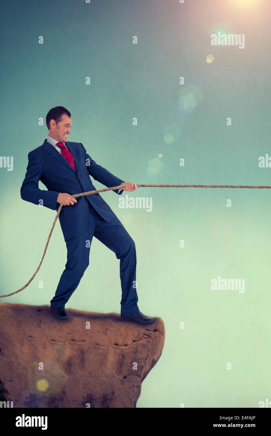tug of war businessman pulling a rope on a cliff edge Stock Photo - Alamy