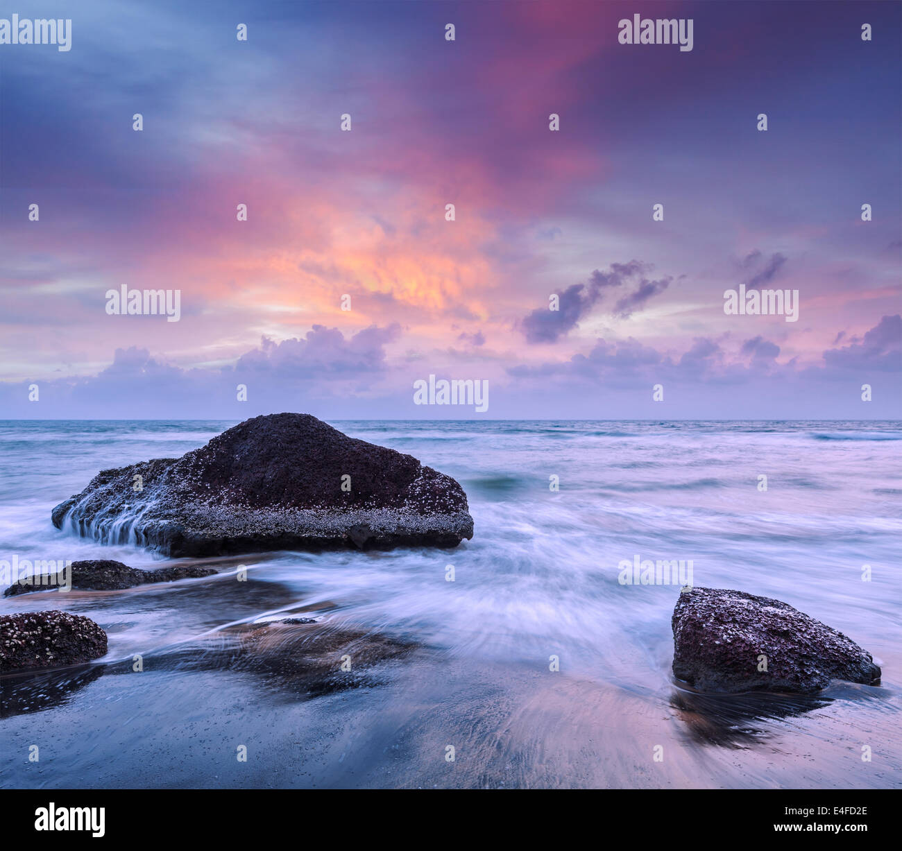 Tropical beach vacation background - waves and rocks on beach on sunset ...