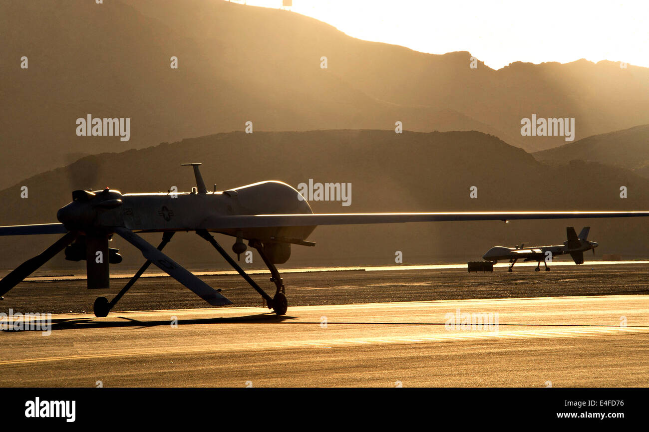 An MQ-1 Predator and MQ-9 Reaper unmanned aerial vehicle taxi to the runway in preparation for take-off at sunset June 13, 2014 Stock Photo