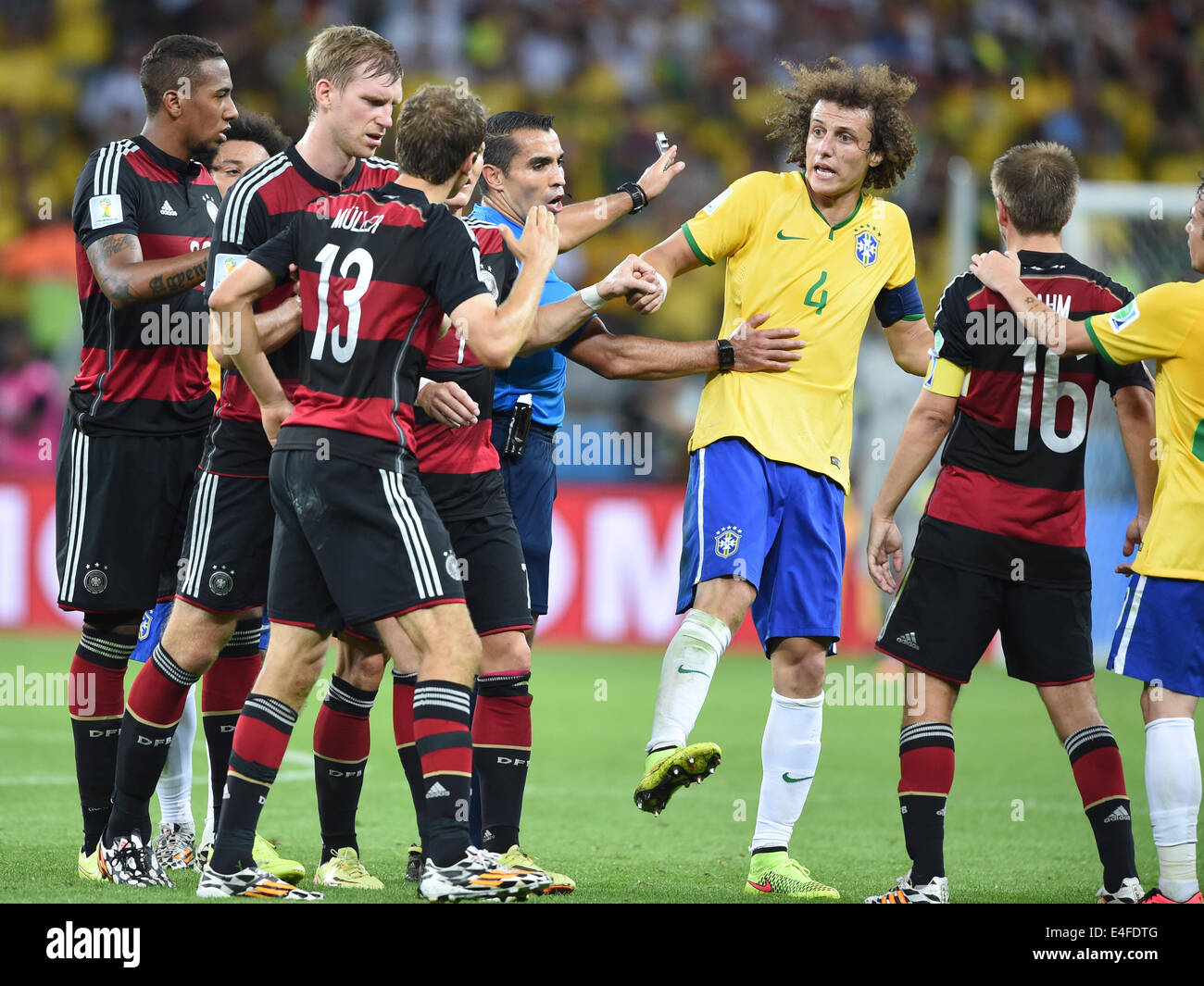 Germany?s Thomas Mueller (13) argues with Brazil's David Luiz (2L) as referee Marco Rodriguez of Mexico separates them during the FIFA World Cup 2014 semi-final match between Brazil and Germany at the Estadio Mineirao in Belo Horizonte, Brazil, 08 June 2014. Photo: Marcus Brandt/dpa (RESTRICTIONS APPLY: Editorial Use Only, not used in association with any commercial entity - Images must not be used in any form of alert service or push service of any kind including via mobile alert services, downloads to mobile devices or MMS messaging - Images must appear as still images and must not emulate m Stock Photo