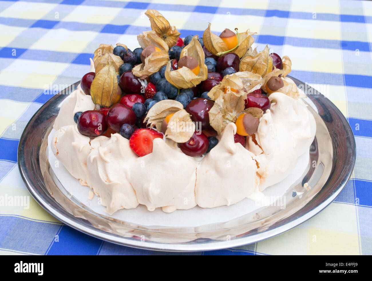 Fresh Fruit Pavlova, meringue topped with fresh fruit including physalis dipped in chocolate on a blue and white tablecloth Stock Photo