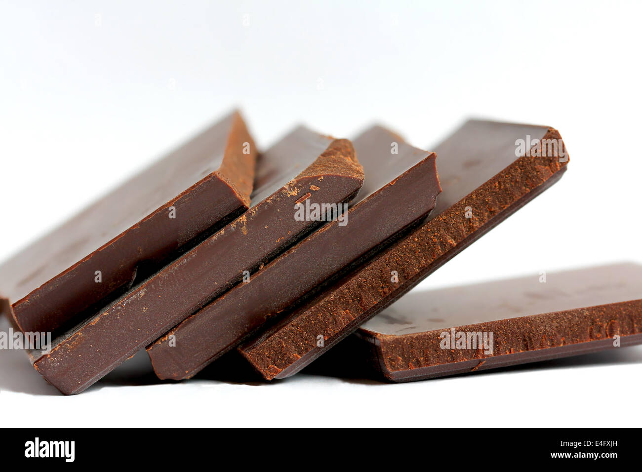 Close up of cut pieces of chocolate on white background, very shallow dof. Stock Photo
