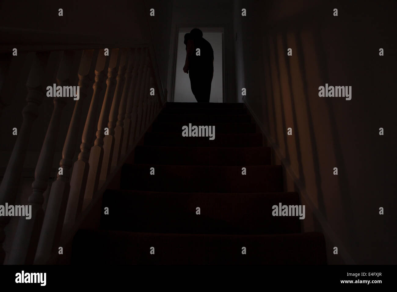 Back view silhouette of a man entering a room at the top of a flight of stairs. Stock Photo