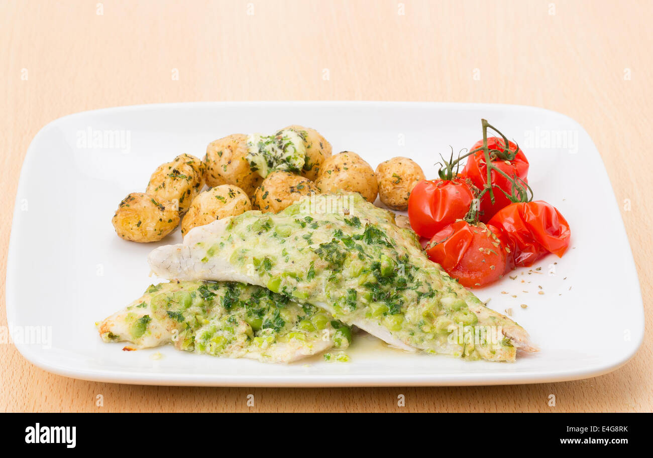 Fillets of Sea Bream served with a garnished coating of pea, creme fraiche and mint, new potatoes and grilled vine tomato Stock Photo