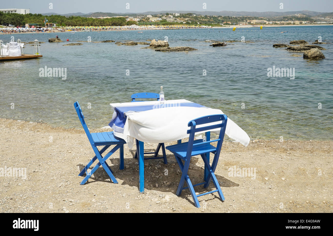 Typically Greek blue restaurant table and chairs beside the sea Stock Photo